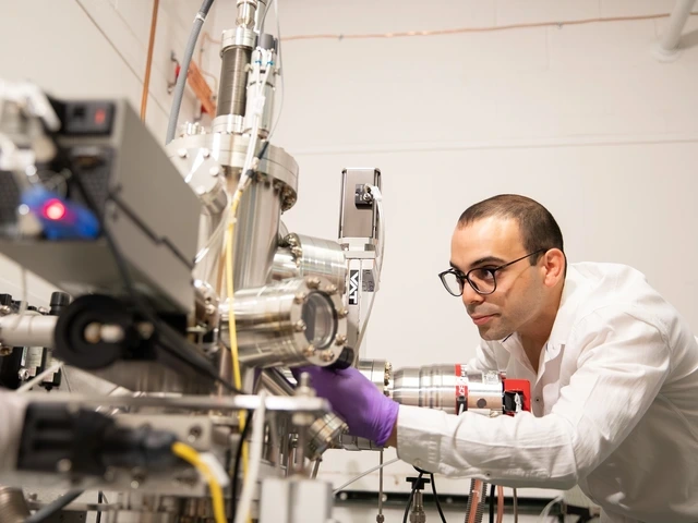 A man with glasses wearing a white lab coat and purple gloves looks at lab equipment
