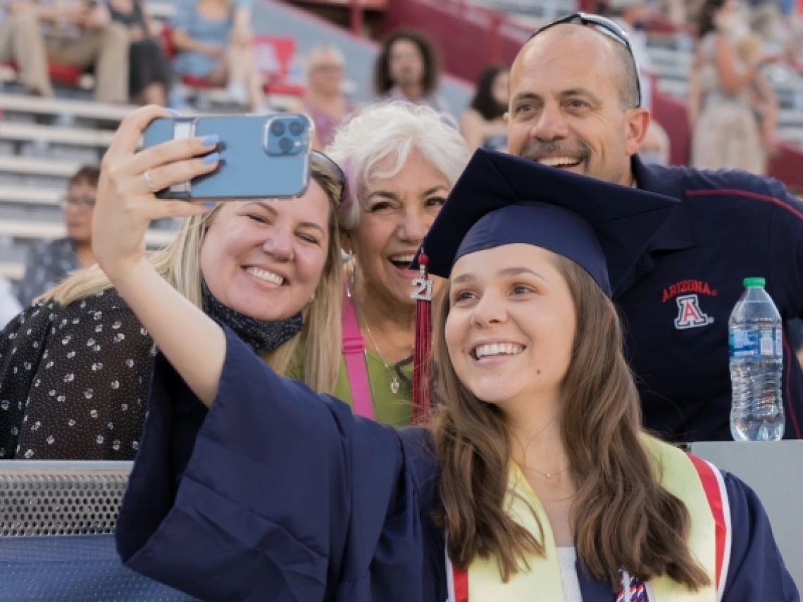 a graduate taking a selfie with parents