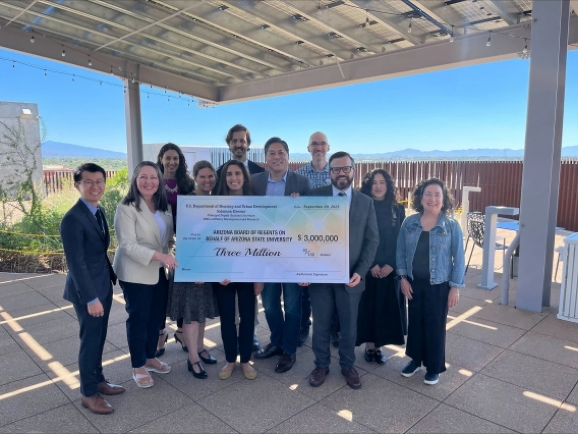 a group of people holding a large ceremonial check worth $3 million