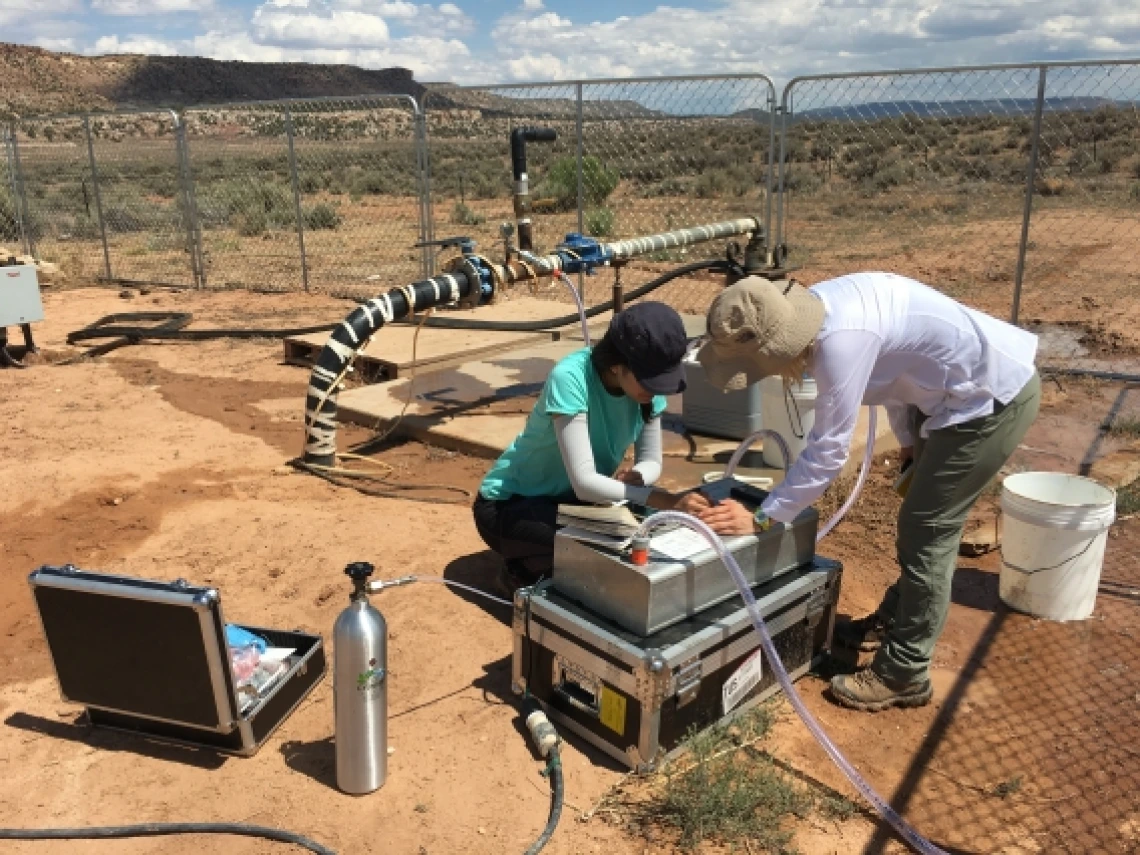 two women working at a machine in the desert