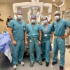 Doctors stand next to a machine in an operating room